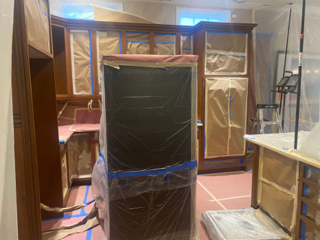 A kitchen with cabinets and appliances carefully taped and covered in preparation for a refinishing project.